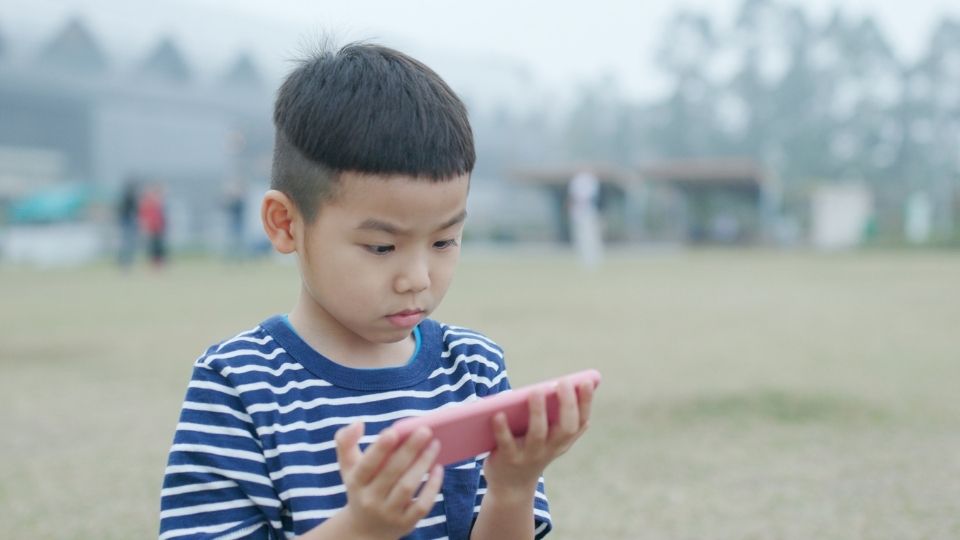 Young Kid Using Smart Phone Outside