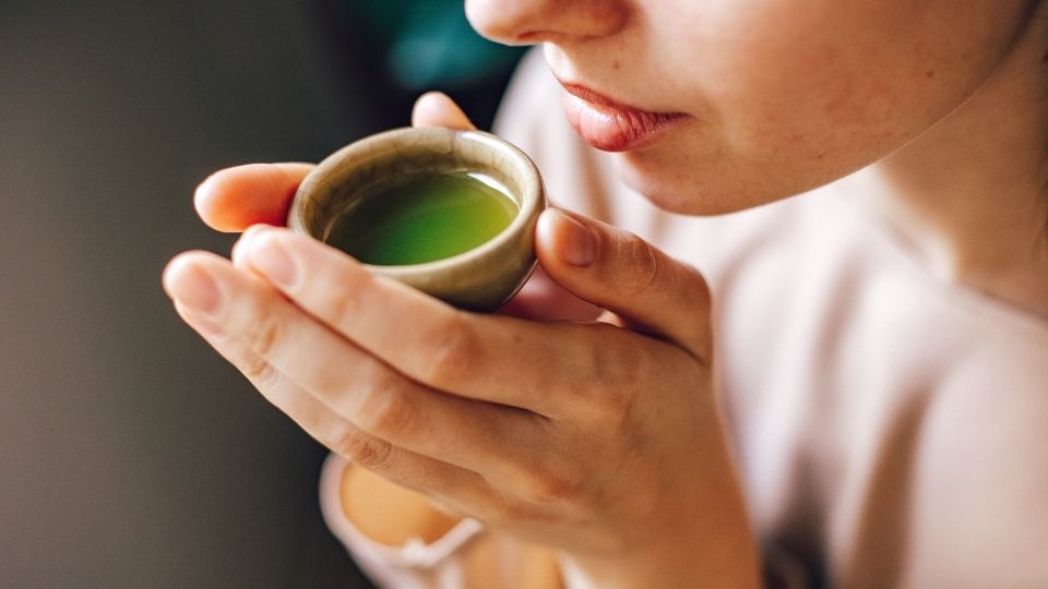 Woman Holding Small Cup of Green Tea